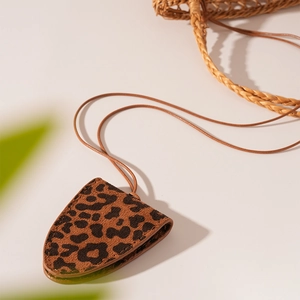 Macro detail of leopard print leather triangle eyewear case with adjustable neck strap