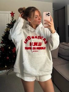 Détail d'un sweat à capuche gris oversize avec broderie Santa Monica rouge devant