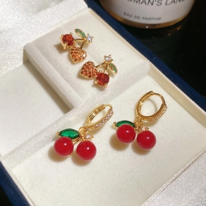 Macro detail of red zircon cherry stud earrings in a cream velvet jewelry box