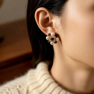 Detailed close-up of a model wearing gold flower earrings with pearls and brown beads