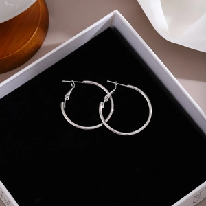 Macro shot of silver hoop earrings in a premium white jewelry box with black velvet lining