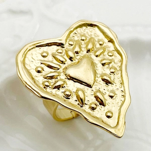 Detailed macro view of golden heart-shaped ring featuring a textured hammered finish