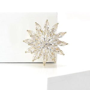 Macro view of rotating golden flower brooch featuring sparkling marquise zircon petals