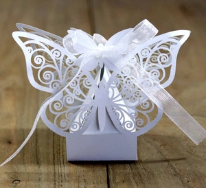 Detail of white laser-cut butterfly wedding favor box with elegant silk ribbon bow