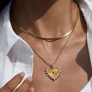Gold layered necklace with ruby heart pendant on a model wearing a white shirt