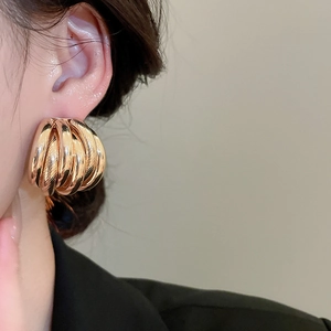 Detail view of large multi-layer gold round earrings worn by a model in a side profile shot