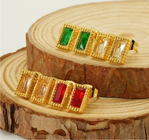 Détail de boucles d'oreilles dorées avec zircons rectangulaires sur bois rustique