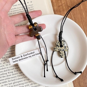 Macro detail of hand-woven wax cord and tiger eye stone flower pendant necklace