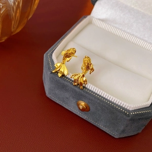 Détail de boucles d'oreilles carpe koi dorées sur un écrin à bijoux en velours chic