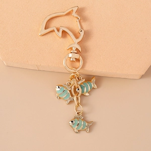 Close-up of golden dolphin carabiner with colorful striped fish charms on a metal keychain