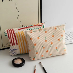 Detail of floral and striped corduroy pouches with zipper and soft ribbed texture