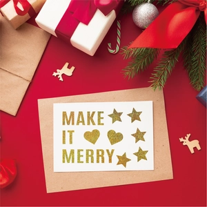 Close-up of 'MAKE IT MERRY' gold glitter Christmas card with craft paper envelope
