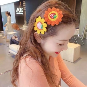 Detailed view of hand-knitted sunflower hair clips with peach and strawberry embroidery