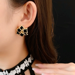 Detail of vintage gold-rimmed earrings featuring black square oil-drop enamel inlay