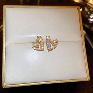 Detailed macro view of heart-shaped gold plated earrings with sparkling zircon inlay