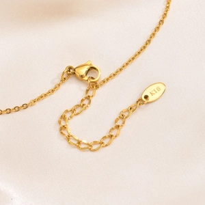 Detailed macro shot of the golden lobster clasp and K18 engraved tag on the heart necklace
