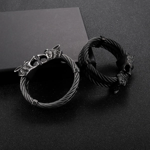 Detailed close-up of viking wolf head bangles with woven stainless steel cable texture