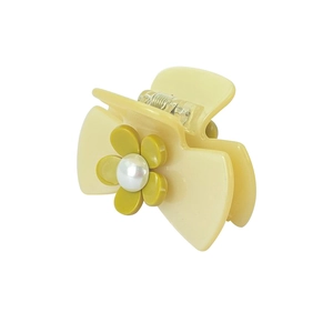 Detail of cream bow hair claw clip featuring olive green camellia flower and pearl