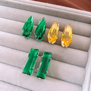 Detail of emerald and amber teardrop earrings with silver-tone prong settings