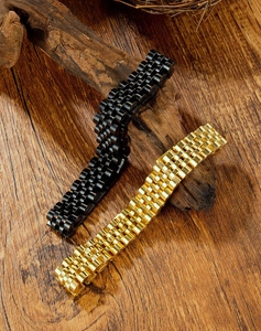 Detail of gold and black stainless steel watch bands on vintage wood background