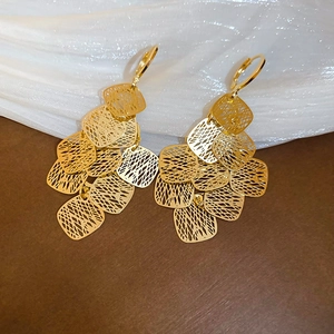 Detailed view of gold geometric hollow tassel earrings on elegant silk background