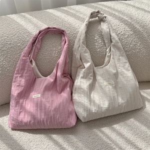 Close-up of pleated fabric texture and brand label on pink and white tote bags