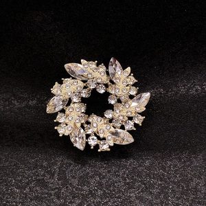 Macro shot of luxury wreath brooch with gold base and clear crystals on black background
