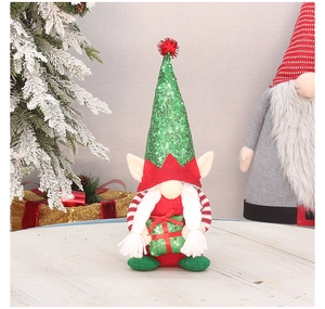 Detail of Christmas elf gnome with green sequin hat holding a gift box on wood surface