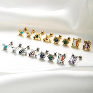Vue à plat de plusieurs boucles d'oreilles fleurs et papillons en zircons dorés et argentés