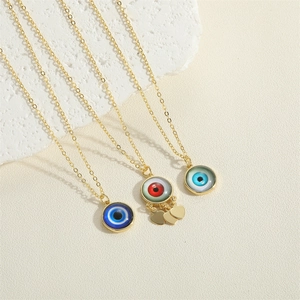 Three gold evil eye necklaces with blue and red zircon heart pendants on a stone tray