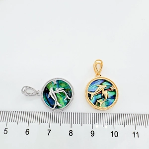 Macro view of 18K gold and silver dolphin pendants with abalone shell inlay on white backdrop