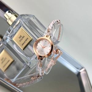 Macro detail of rose gold quartz watch face with small diamond markers and chain band