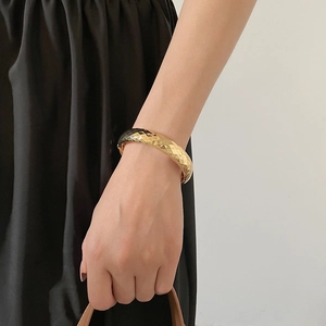 Détail de la texture géométrique dorée facettée sur un bracelet jonc ouvert minimaliste
