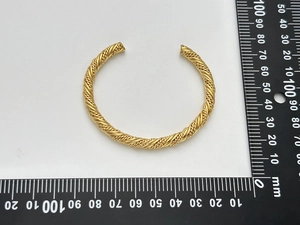 Detailed top view of a gold twisted cuff bracelet with ruler showing 65mm diameter