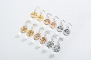 Detail of hollow tree of life and hamsa hand earrings with elegant white pearls
