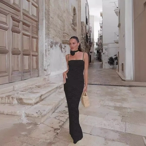 Eng anliegendes schwarzes Spitzen-Maxikleid mit Textur und Strohhandtasche in der Straße