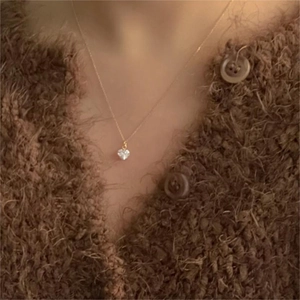 Close-up of elegant gold heart pendant necklace with clear crystal on a model