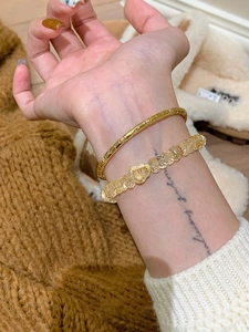 Détails d'un jonc doré bambou et bracelet en perles avec breloque en cœur