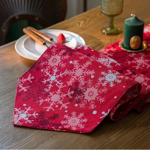 Deep red Christmas table runner with white snowflake patterns on a rustic wooden table