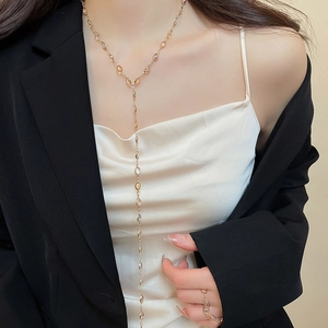 Close-up of a gold Y-shaped necklace and matching ring with clear crystals on a model