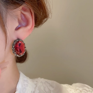 Macro shot of vintage style oval earrings with dark red stones on a model's ear