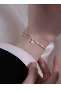 Close-up of a silver double-layer bracelet with star pendant and sleek metal bangle