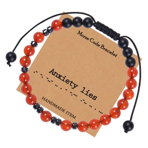 Detail of Morse code bracelet with red and black beads on a Kraft gift card