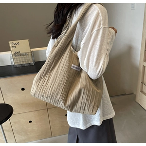 Detail der beigen Schultertasche mit Faltenstruktur und Kiss Yourself Etikett
