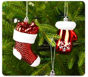 Gros plan de chaussettes et moufles de Noël rouges brillantes sur un sapin vert