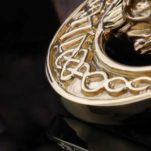 Macro view of gold stainless steel lion pendant featuring intricate Celtic knot relief