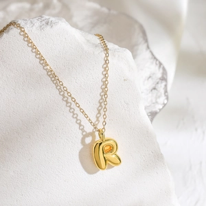 Collana minimalista placcata oro 26 lettere con ciondolo R 3D su una base in pietra