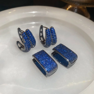 Macro shot of dark blue zircon earrings in gunmetal grey finish on a white stone tray