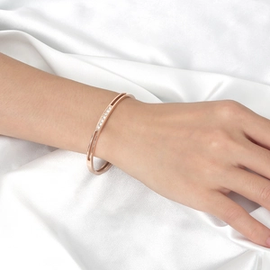 Rose gold stainless steel bracelet with seven white zircon stones on silk background