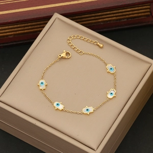 Detail of gold Hamsa Hand and Evil Eye charms on an adjustable stainless steel bracelet